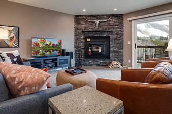 A cozy and well-appointed living room at Ranch at Steamboat RA511, featuring a stone fireplace, comfortable seating, and a large window with a view of a snowy mountain.