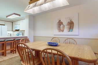 The dining area in Enzian 116 features a wood table with seating and art on the wall.