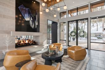 The contemporary living room at Lone Star Lodge Mountain Village features a modern fireplace, stylish seating, and large windows revealing a snowy landscape.
