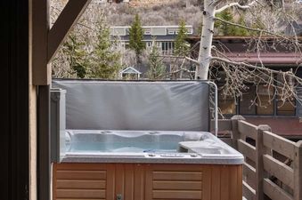 The private hot tub on the wooden balcony at Portico Pines, overlooking a scenic hillside.