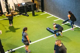 A bright and modern indoor gym with turf flooring and various training equipment.