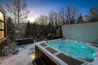 An outdoor hot tub with glowing blue water sits on a snowy patio surrounded by bare trees in winter at Silverado.