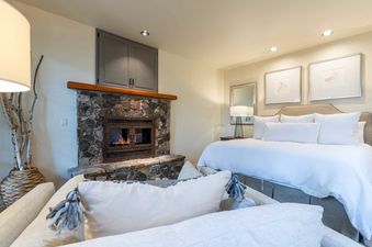 A bedroom with a fireplace and a large bed with white linens.