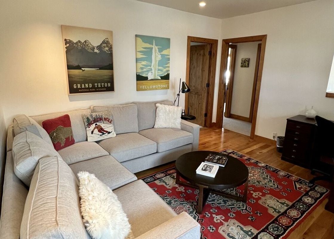 A cozy lounge area in Granite Ridge Lodge 17 with an L-shaped sectional sofa and a patterned red rug.