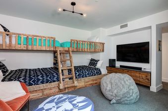 A bunk bed with a TV on the wall in a kids' room at Moonlight Basin 12 Lake Cabin.
