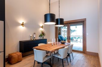 A modern dining room at Northern Lights 32 with a wooden live-edge table, cream chairs, and black pendant lights.