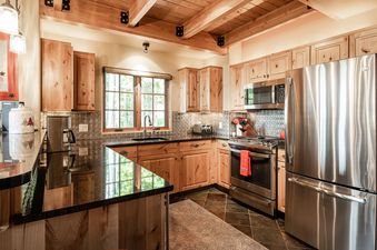 The kitchen in Moonlight Basin 4 Full Moon features stainless steel appliances and a view of the trees.
