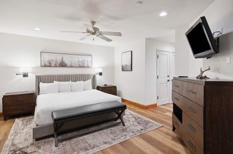 A primary bedroom in The Charter L223 featuring a king-sized bed, dark wood furniture, and nature-inspired artwork, designed for comfort and relaxation.