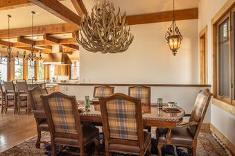 Dining area of Hitch Haven 3041 with an antler chandelier, wooden table, and kitchen in the background.