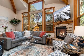 The inviting living area at Abode at Dawn Patrol features a stone fireplace, comfortable seating, and large windows that offer views of the surrounding landscape.
