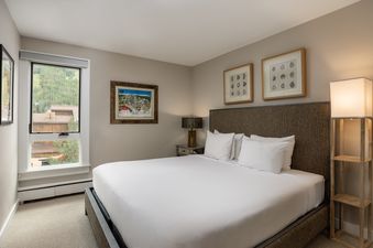 A primary bedroom at Vail 21 407, featuring a king-sized bed, elegant decor, and a window with mountain views.