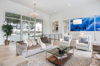 A spacious, modern living room at Quicksilver Haus with plush seating, a large glass-top coffee table, and expansive windows offering a view of a snowy landscape.