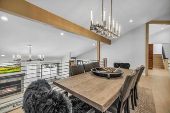 The dining room at Last Run Luxury features a large wooden table with black leather chairs and antler decorations, illuminated by a modern chandelier.