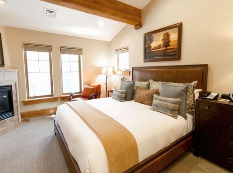 Luxurious bedroom at The Chateaux Deluxe One Bedroom featuring a large bed, fireplace, and warm, inviting atmosphere.