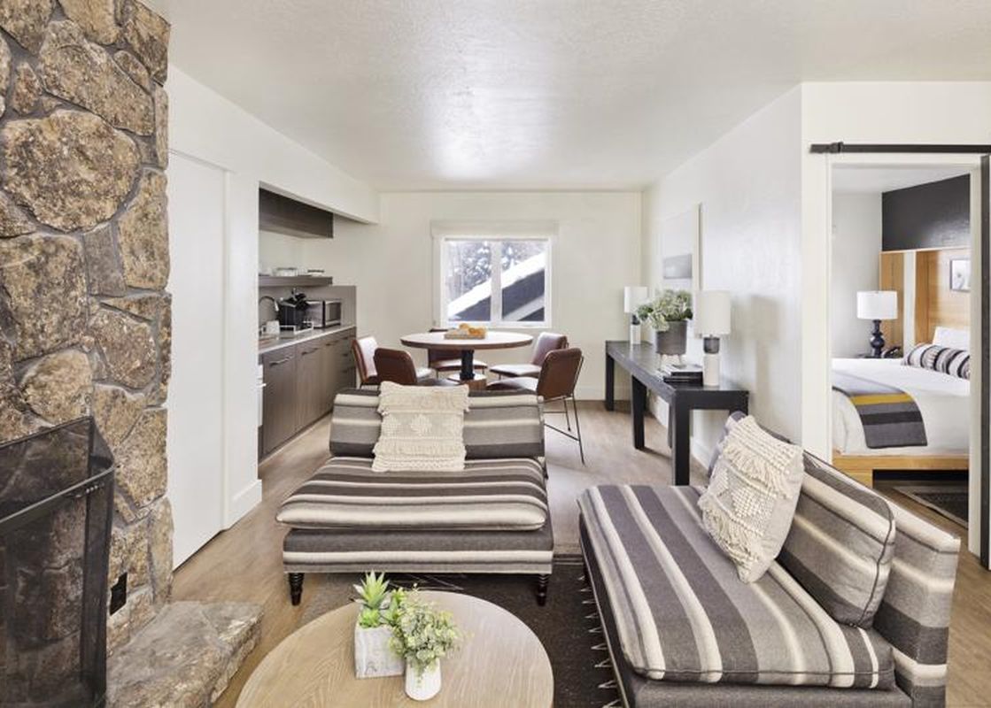 Modern and cozy living area of the Gravity Haus JH One Bedroom King Suite with stone fireplace and view of the bedroom.
