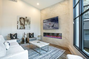 The living area of Vail Center Place 2 Bedroom Diamond Unit 2 features a large white couch, a marble coffee table, a flat-screen TV, and an electric fireplace, creating a luxurious and comfortable space.