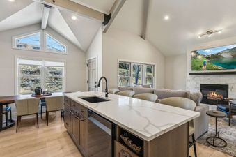 An expansive open-concept living area with a modern kitchen, dining space, and a cozy living room featuring a fireplace and flat-screen TV.