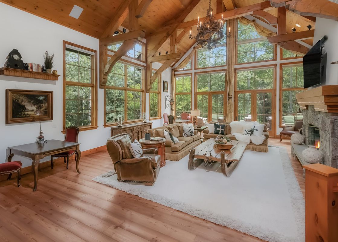 Pine Meadow Estate's living room features a beautiful fireplace and a large white rug.