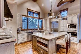 The kitchen at Monarch at Shock Hill features stainless steel appliances, a large center island, and a view of snow-covered trees outside the window.