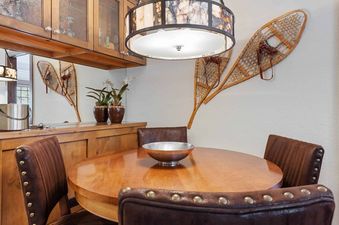 A cozy dining area at The Charter D340 featuring a round wooden table, leather chairs, and rustic decor including snowshoes on the wall.