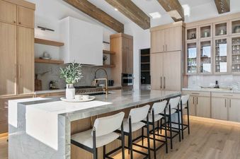 Modern open-concept kitchen with a large marble-top island, light wood cabinets, and stylish bar stools.