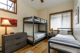A bedroom with a bunk bed, a single bed, and a dresser.