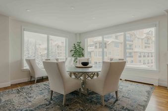 Summit View Chalet dining room with a large table and chairs with an exterior view of snowy trees and buildings.