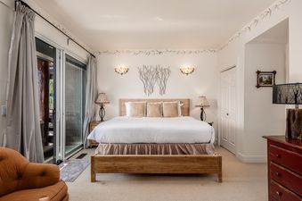 The master bedroom at Moonlight Basin Saddle Ridge F5 features a king-size bed with white linens, a wooden headboard, and two lamps on nightstands.