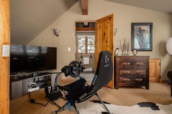 Moonlight Basin 2 Mountain Home's entertainment room has a large flatscreen TV, a gaming chair, and a comfortable rug for relaxing.