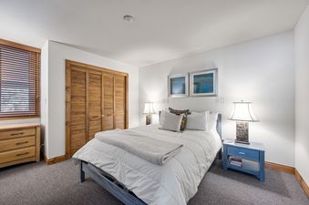 A cozy bedroom at Three Kings Powder Lodge with a large bed, two bedside tables with lamps, and a wooden closet.
