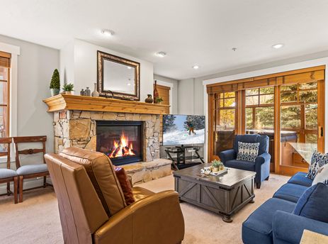 A cozy living room with a lit fireplace, a blue sofa, and a large television, offering a perfect blend of comfort and entertainment.