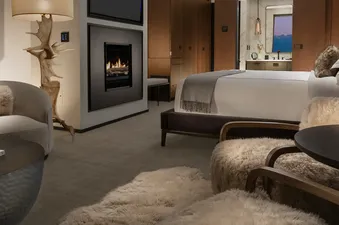 A luxurious bedroom and living area in the Grand Reflection Suite, featuring a fireplace, a comfortable bed, and stylish decor.