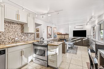 An inviting open-concept living area and kitchen with modern appliances and a cozy fireplace in Silverglo Condominiums 205.