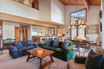 A spacious living room with two sofas, a coffee table, and a large window overlooking a wooded area.
