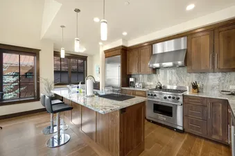 Modern and elegant kitchen at On Trails Edge featuring premium wooden cabinets and a granite island with bar stools.