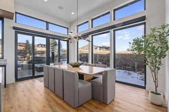 A dining room with large windows overlooking a snowy mountain landscape.