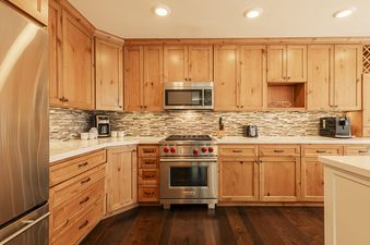 The kitchen at Deer Valley Daystar 1793 features light wood cabinetry, stainless steel appliances, and a tiled backsplash.