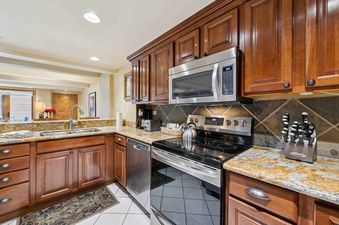 Stainless steel appliances, granite countertops, and dark wood cabinets are featured in this kitchen.