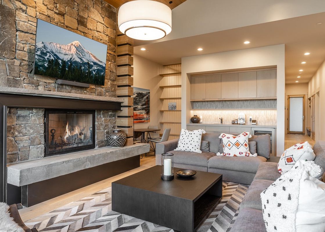 Moonlight Basin 80B Lodgeside living room with a fireplace, stone walls, and a large sectional sofa