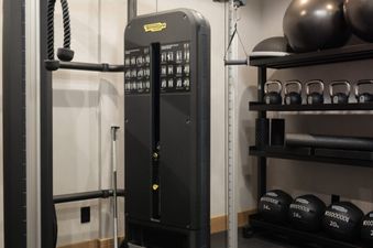 A well-equipped fitness center featuring Technogym exercise equipment, kettlebells, and stability balls.