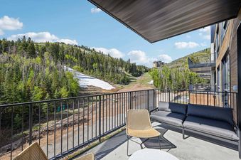 A private balcony at Founders Place 2405 with outdoor furniture overlooks a snow-covered mountain ski slope surrounded by green trees.