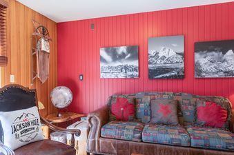 Cozy living area at Windriver 12 featuring a red paneled wall, mountain artwork, and rustic decor.