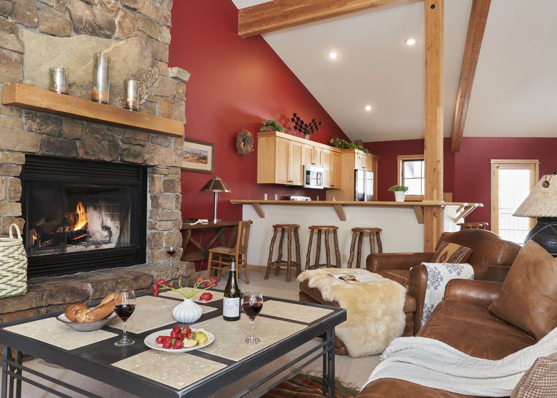 Cozy living room in Moose Creek 30 featuring a large stone fireplace, leather seating, and a kitchen bar.