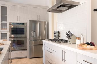 A modern kitchen with light wood cabinets, stainless steel appliances, and a kitchen island with a gas cooktop.