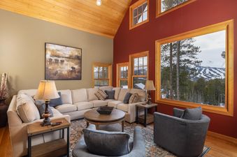 A spacious living room with large windows overlooking snowy mountains.