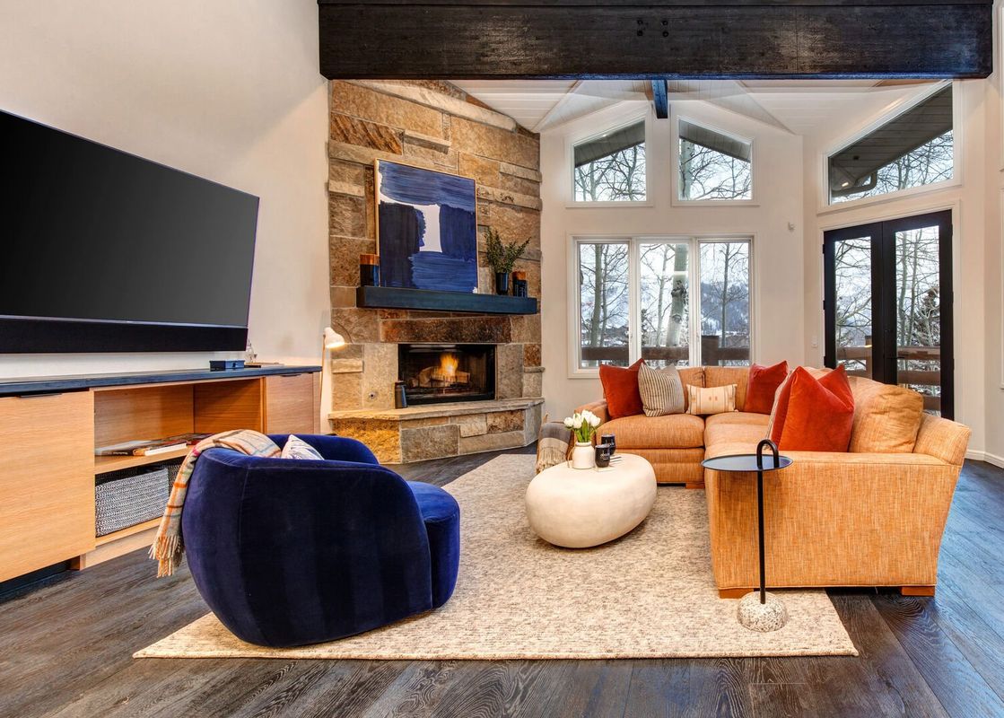 Twin Pines Home living area features a large sectional sofa, plush armchair, and a fireplace with a stone surround.