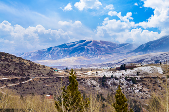 A scenic view of a snow-dusted valley with mountains under a bright blue sky.
