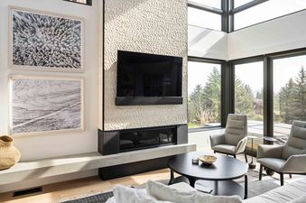 A modern living room with a fireplace and a large window overlooking a view of trees.