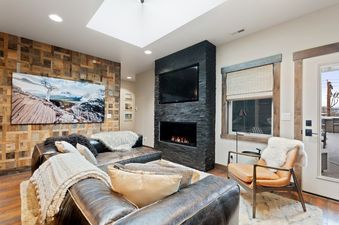 A luxurious living room at Central Loft 303 with a large sectional sofa, a fireplace, and a flat-screen TV, featuring rustic wooden accent walls.