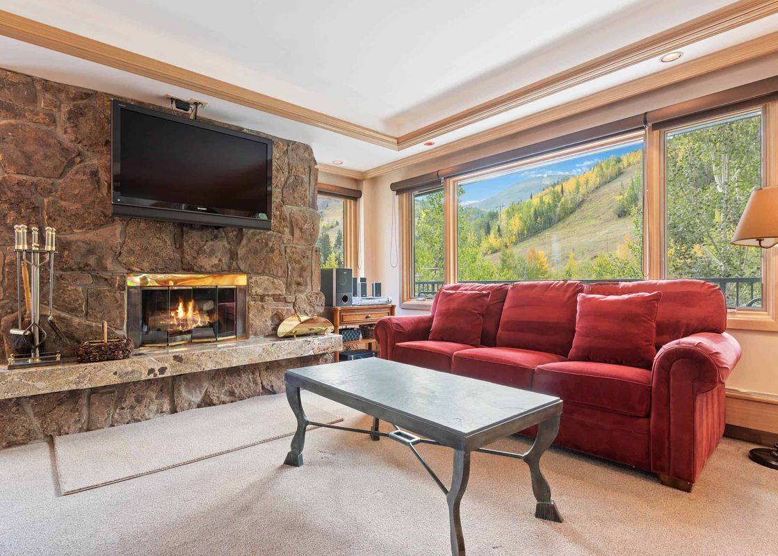 The living room of Lodge Tower 377 3BR is warmly decorated with a stone fireplace and comfortable red couch.